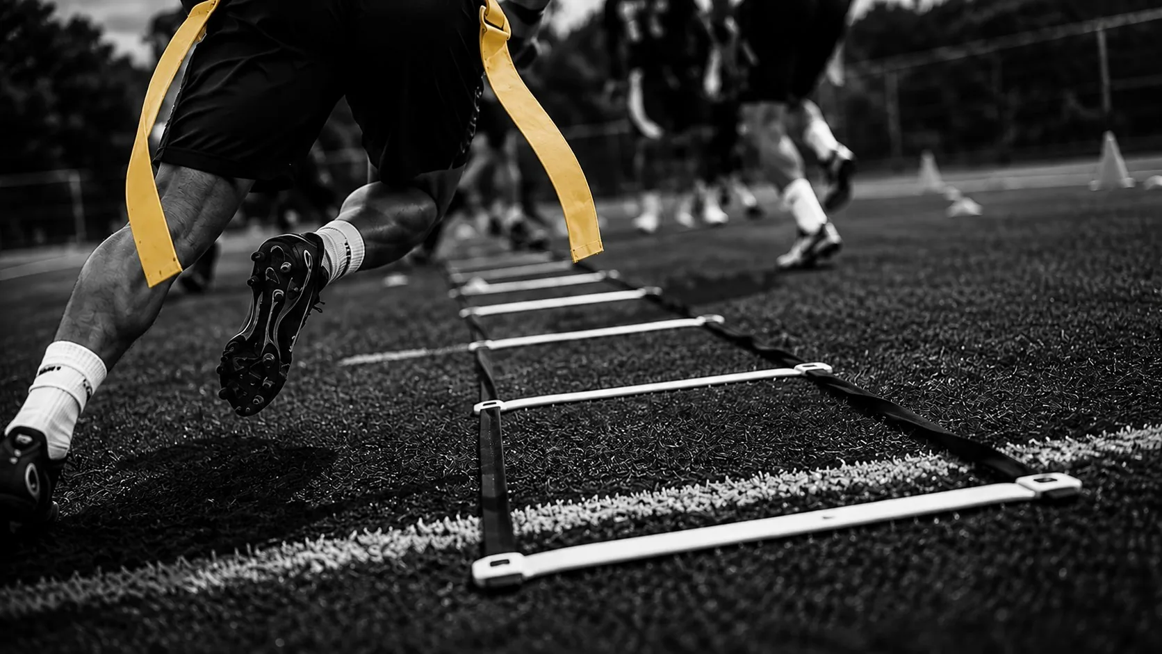 Charros player driving through an agility ladder drill on turf